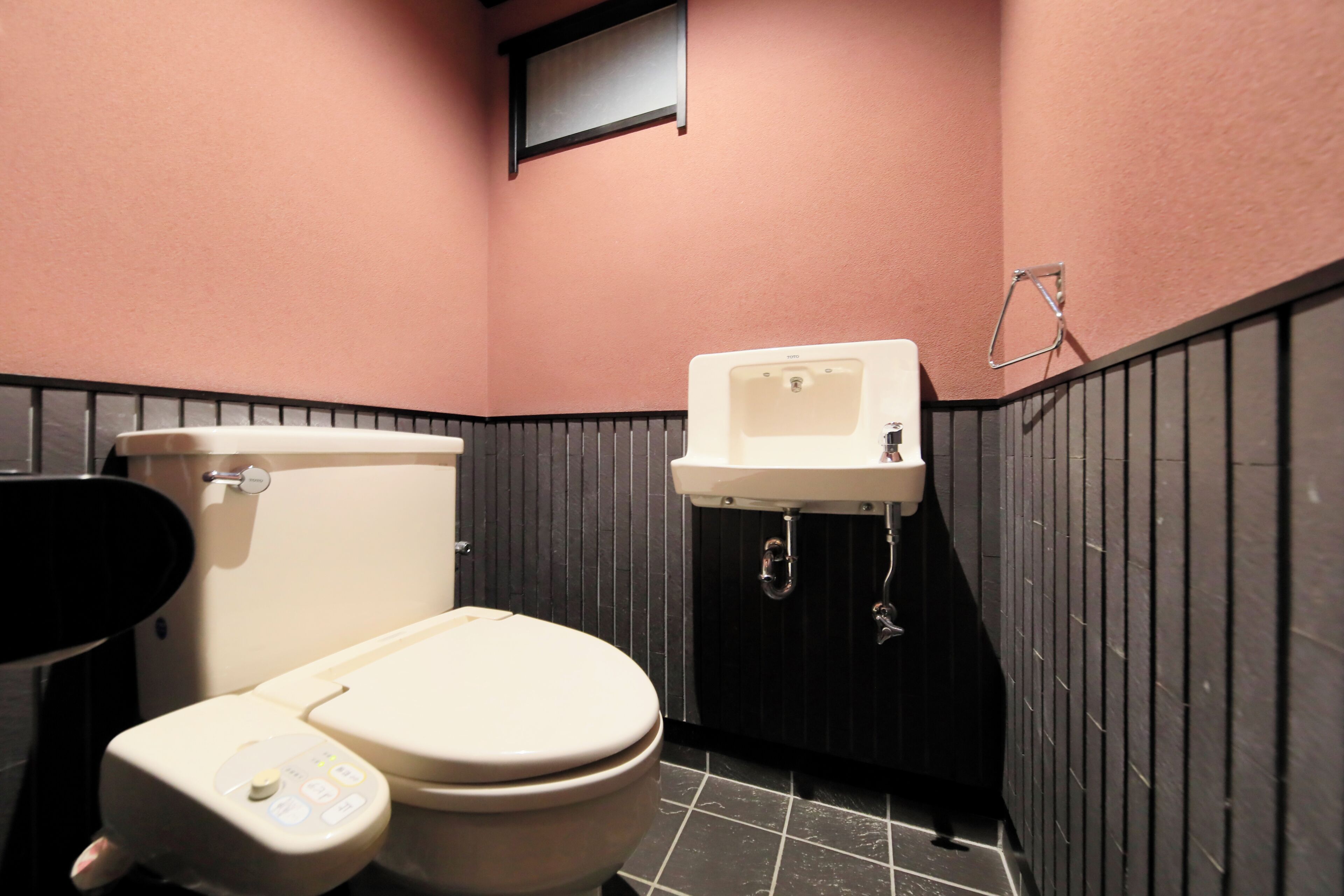 Une salle de bain avec des toilettes, un lavabo et une petite fenêtre.
