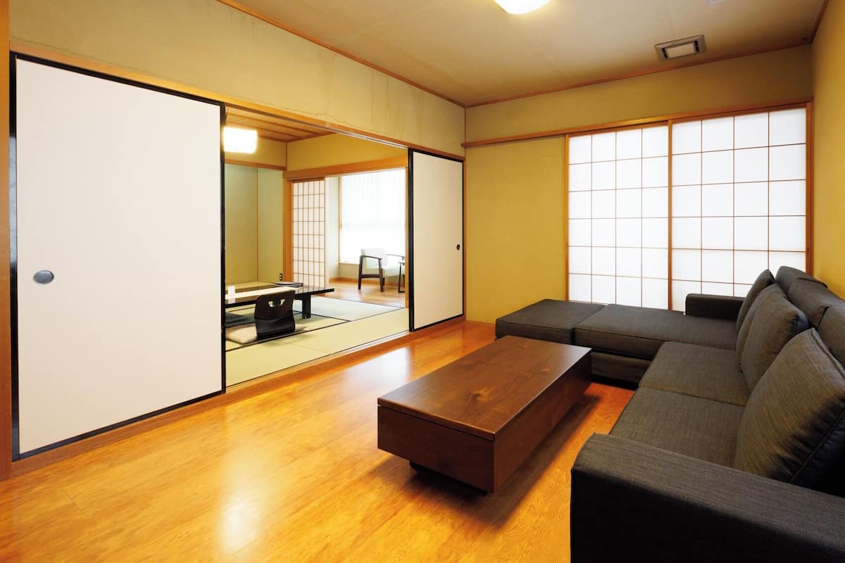 A modern living room with a sofa, a wooden coffee table, sliding doors, and large windows.