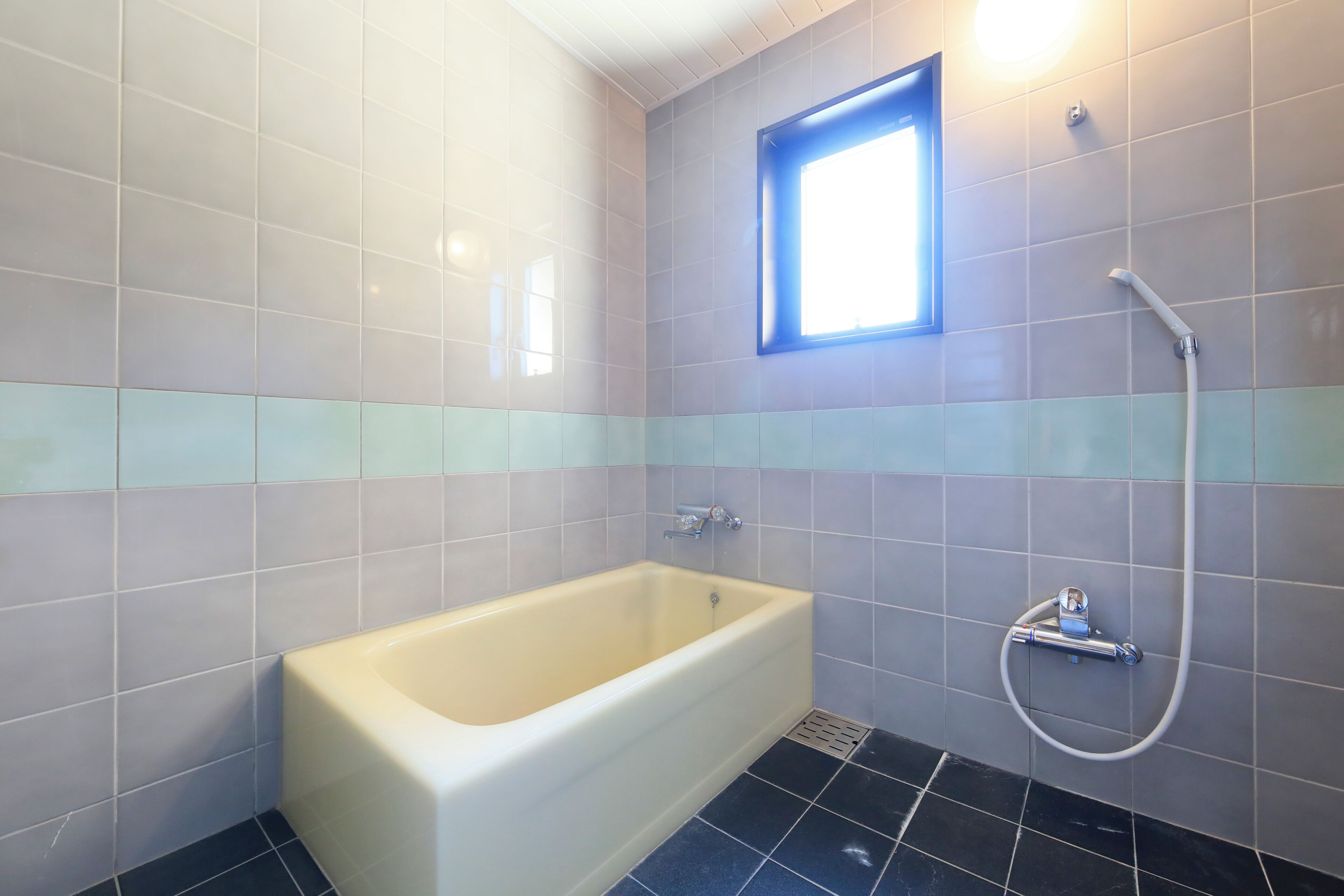 A bathroom with a bathtub, a shower, and a window.
