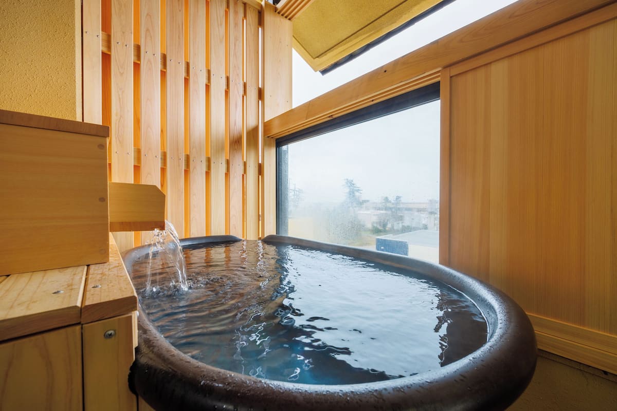 A wooden interior with a hot tub and a window providing a view of the outside.