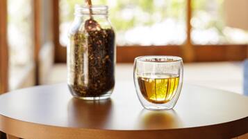 A glass jar with a spoon and a glass of tea on a round table.