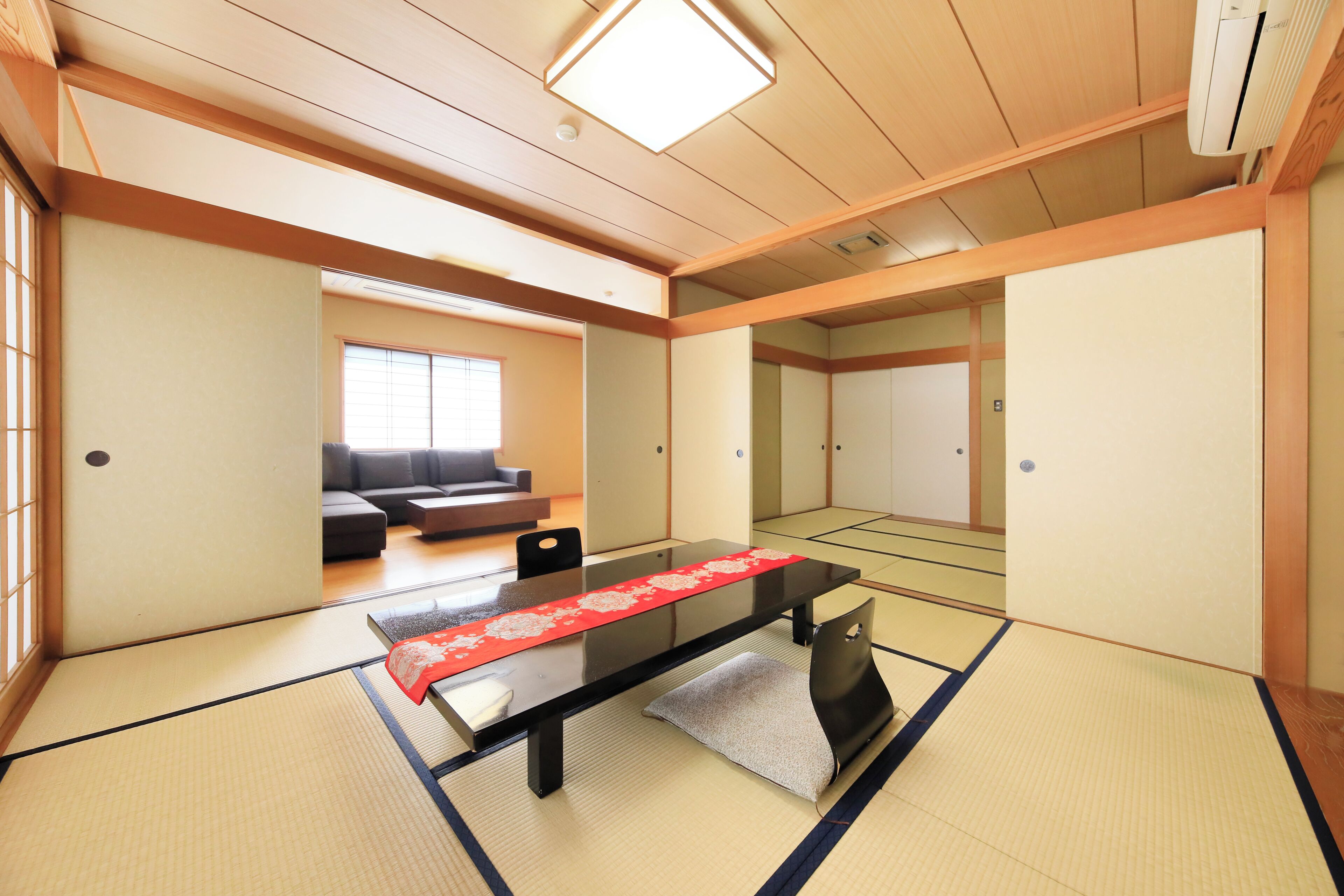 A tatami mat room with a low table, a sofa, and a sliding door.
