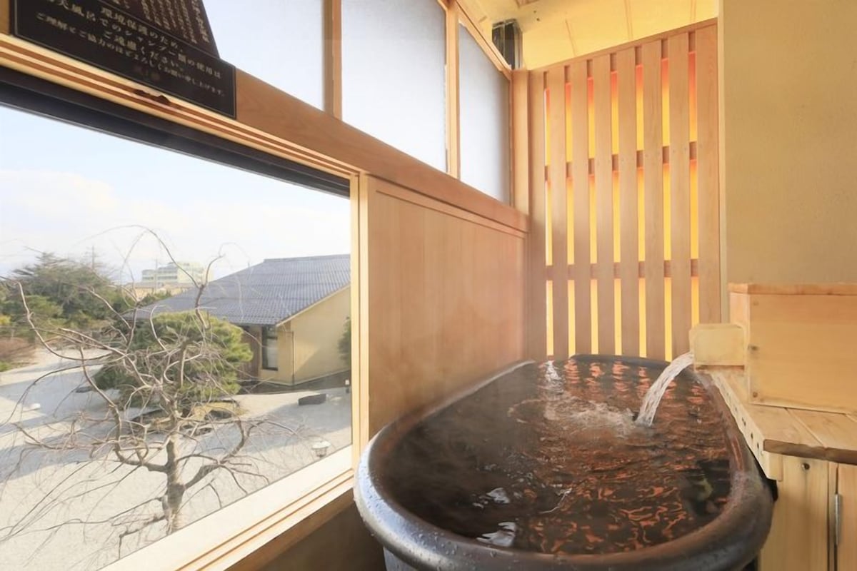 A hot spring bath with a wooden partition and a view of the outside.