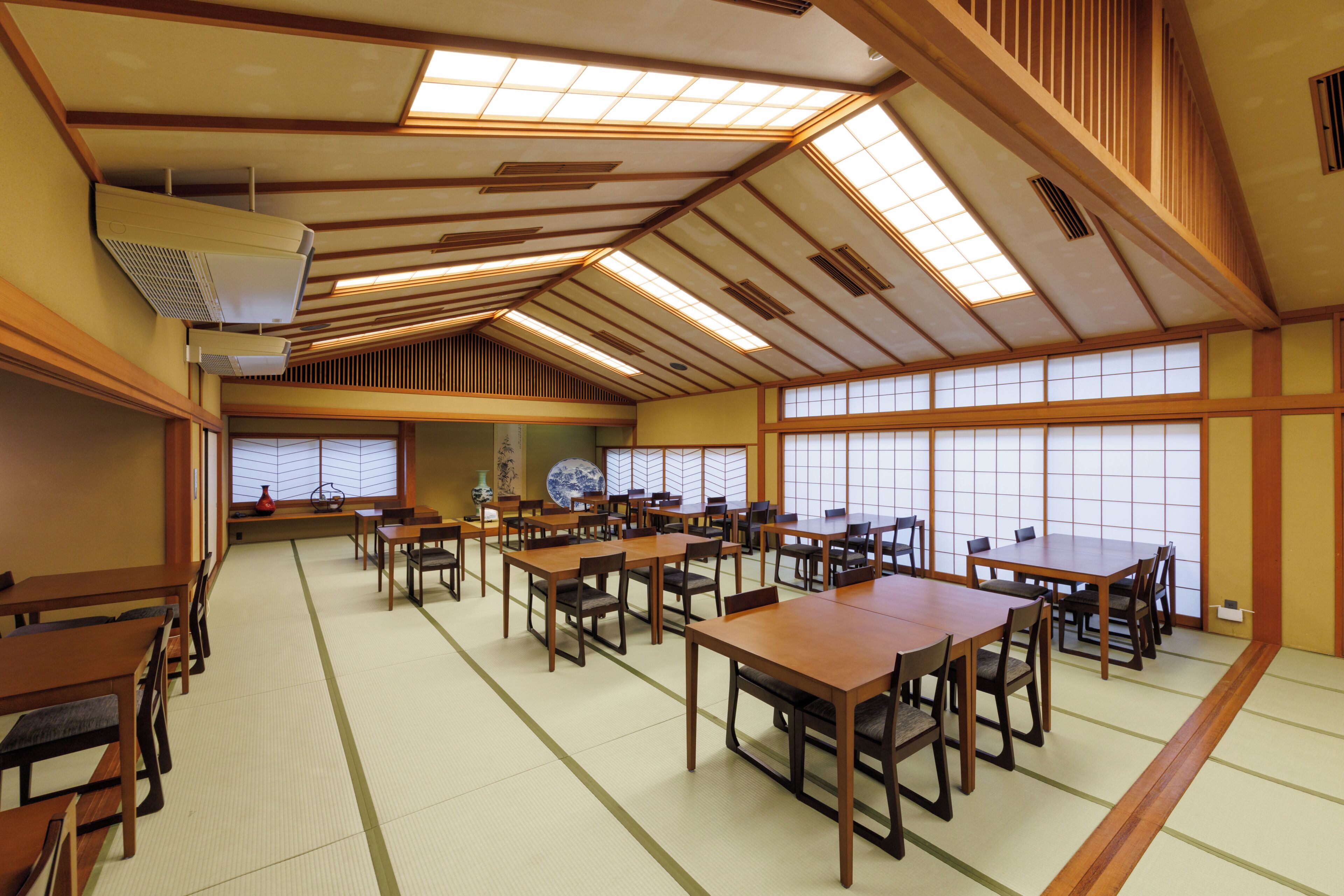A traditional Japanese-style room with tatami flooring, wooden tables, and sliding doors.
