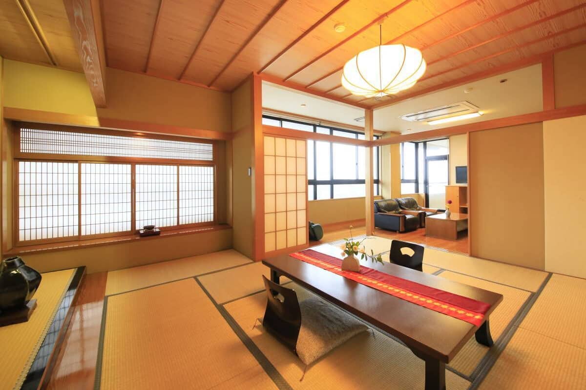 A traditional Japanese room with tatami flooring, a low table, and sliding doors.
