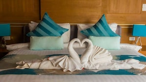 Habitación de hotel con una cama decorada con una grúa de toallas y almohadas a rayas azul turquesa.