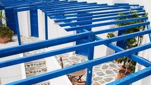 A blue balcony with white walls, potted plants, and a small table. - Manousos' Rooms (Syros)