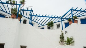 A white building with blue accents, including a blue staircase and railings. - Manousos' Rooms (Syros)