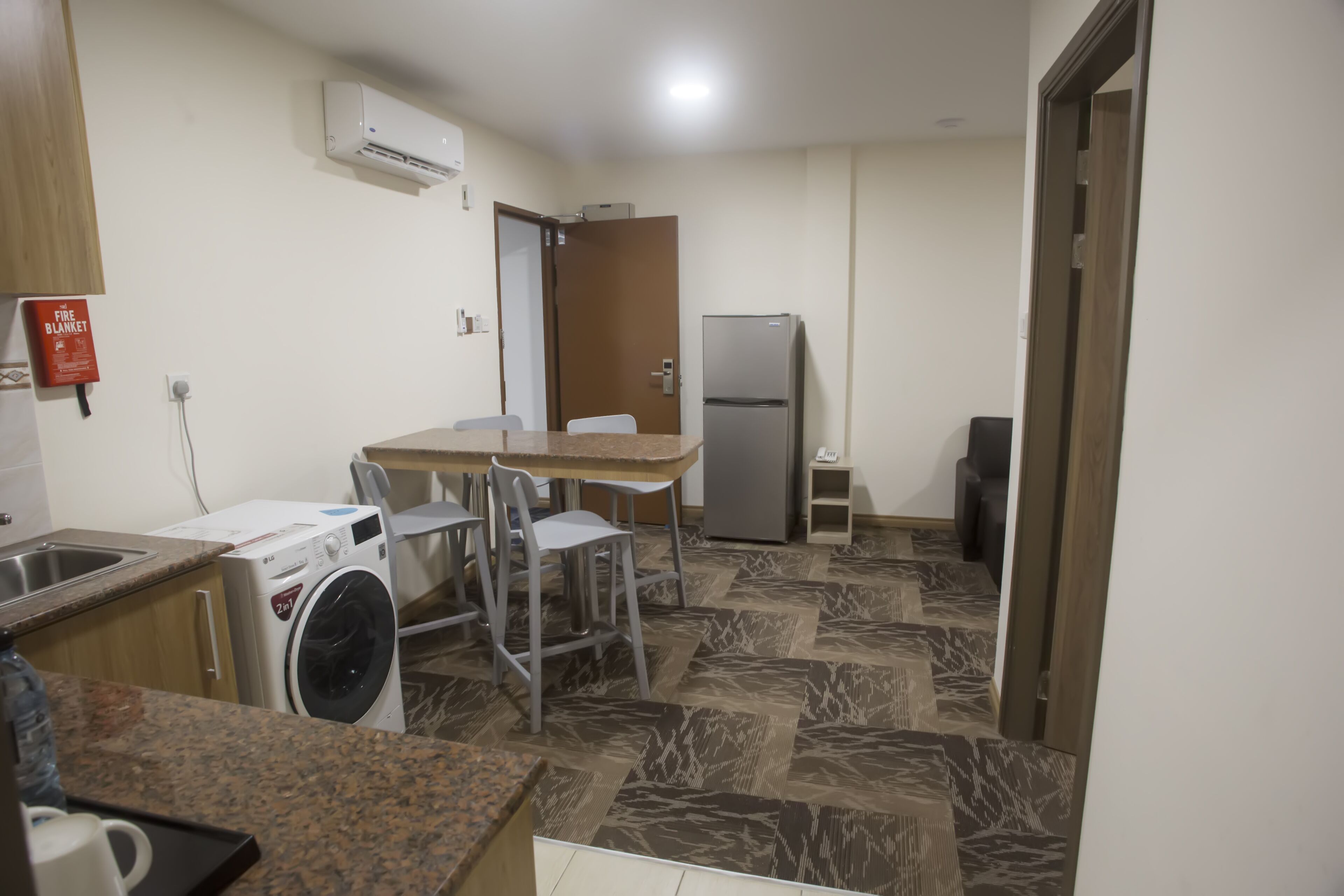 Una cocina compacta con lavadora, refrigerador y comedor con sillas.