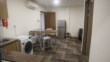 Una cocina compacta con lavadora, refrigerador y comedor con sillas.