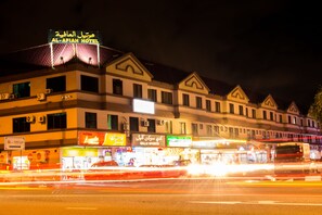 Un hotel con un letrero que dice 'Al-Afiah Hotel' y varios comercios abajo.