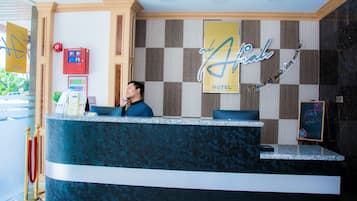A hotel reception desk with a check-in counter, a red emergency box, and a sign that reads "Atahual Hotel".