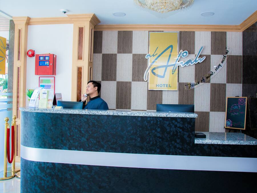 A hotel reception desk with a check-in counter, a red emergency box, and a sign that reads "Atahual Hotel".