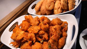 Two white plates filled with golden-brown fried food items, likely fritters, on a kitchen counter.