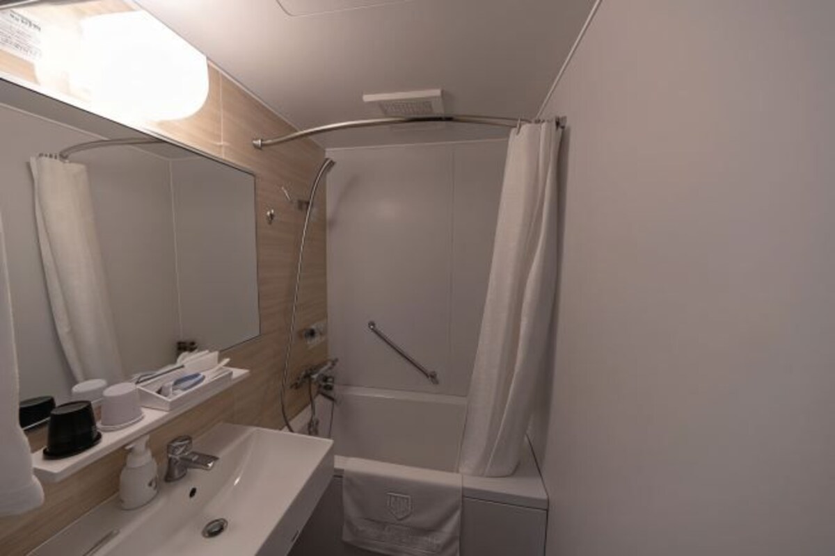 A modern bathroom with a sink, mirror, and shower area.