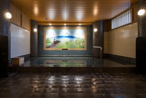 A modern indoor swimming pool with a mural of Mount Fuji and a steam train.