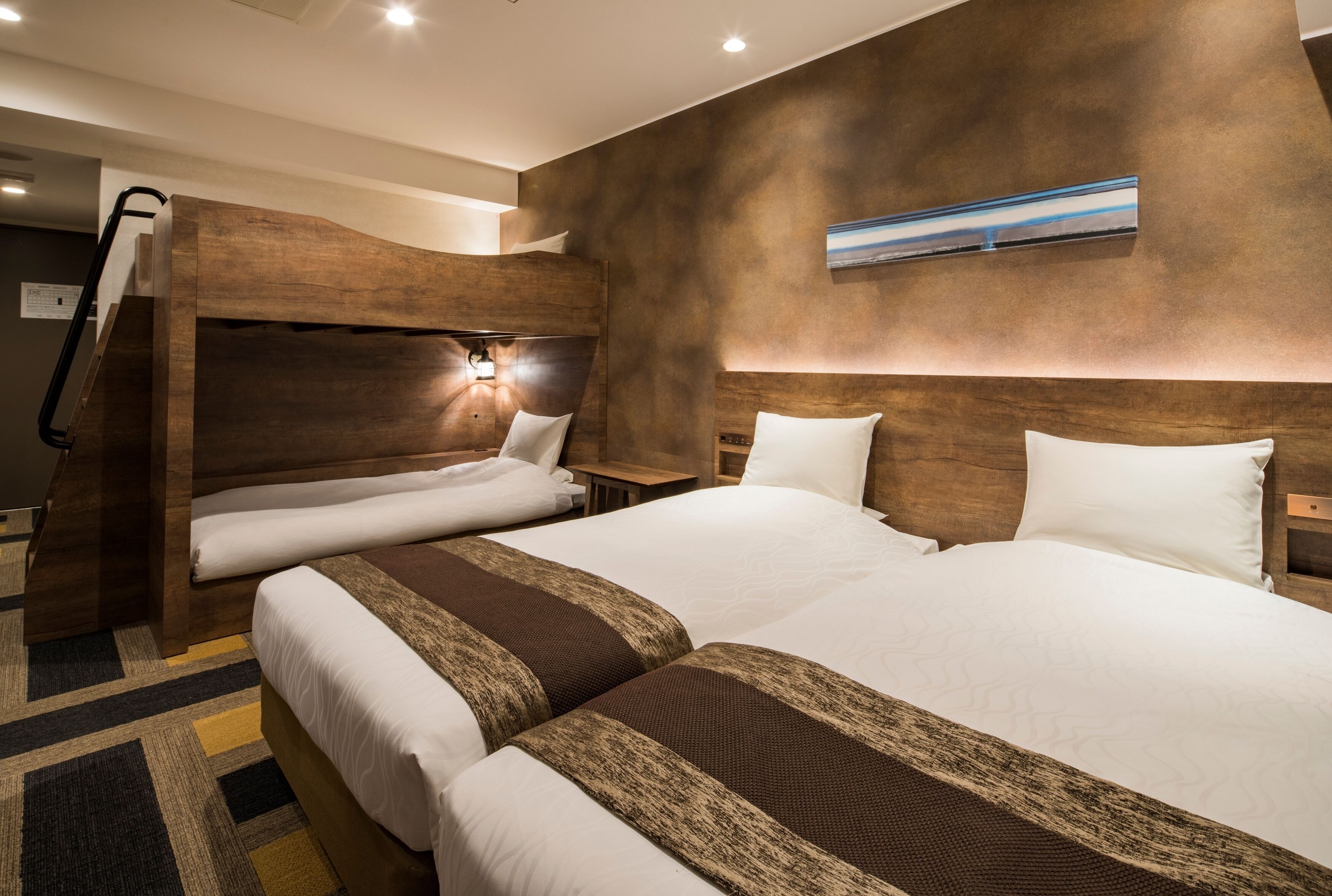 A hotel room with two beds, a wooden headboard, a nightstand, and a painting on the wall.