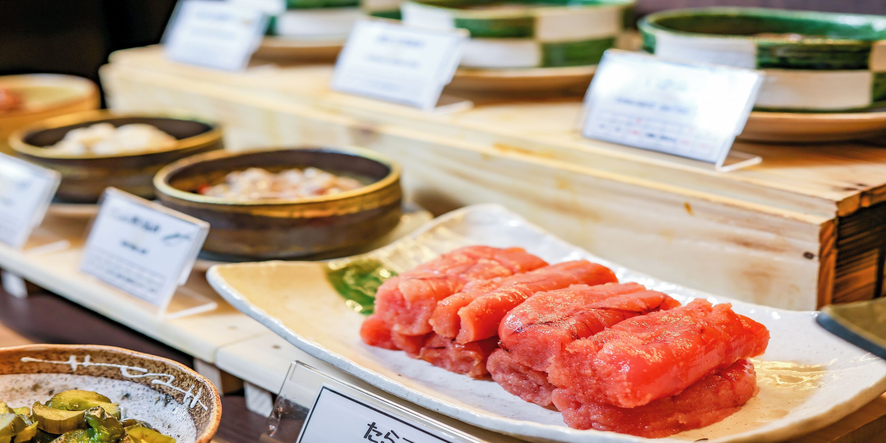 A food display with various dishes, including a prominent plate of sliced meat and several bowls of different foods.