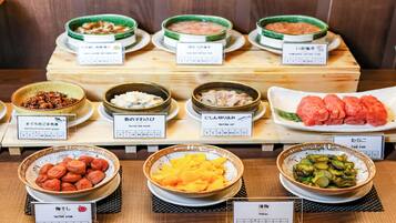 A variety of Japanese dishes displayed on a wooden table with labels in Japanese.