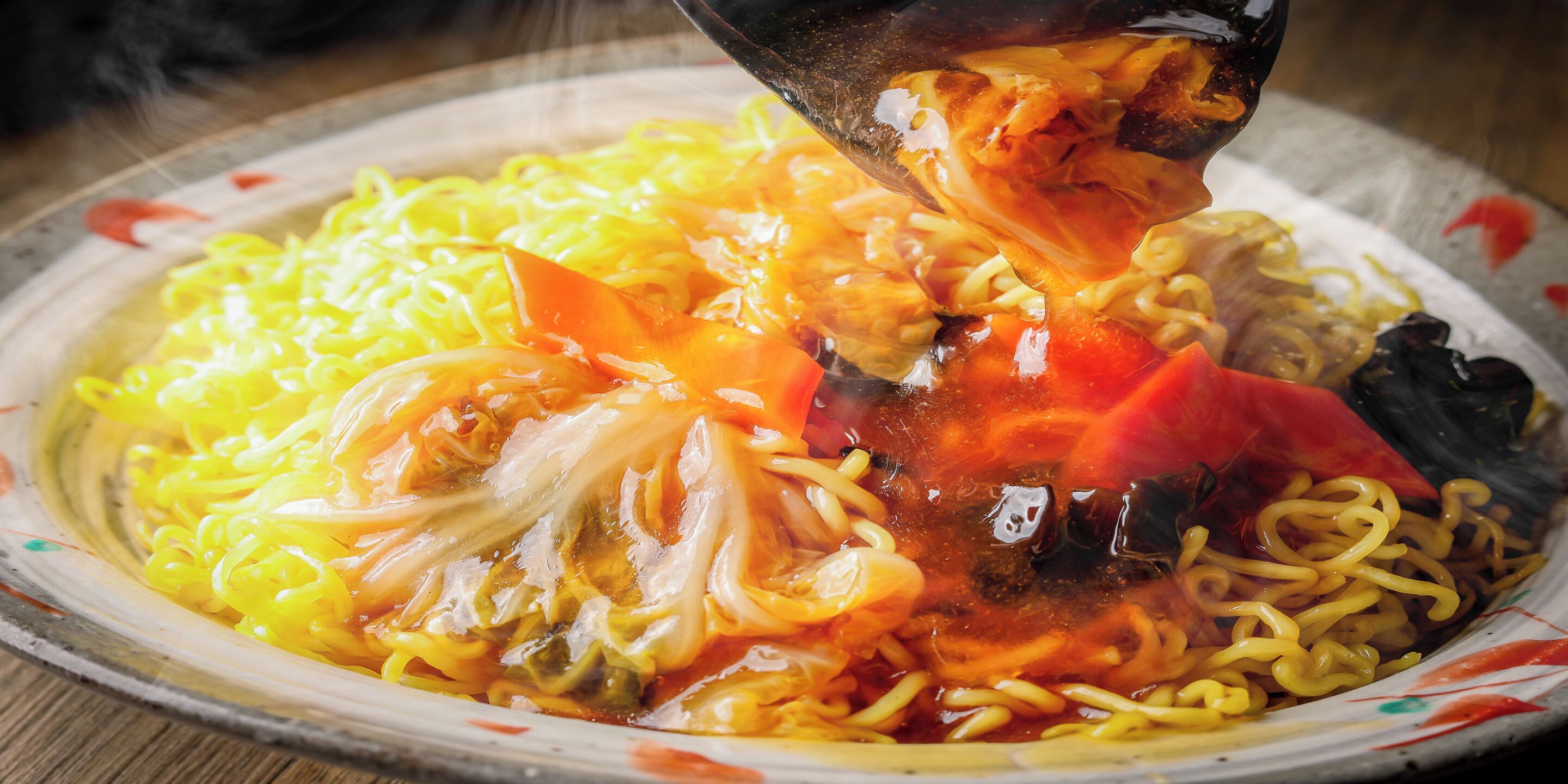 A bowl of noodles with vegetables and a sauce.