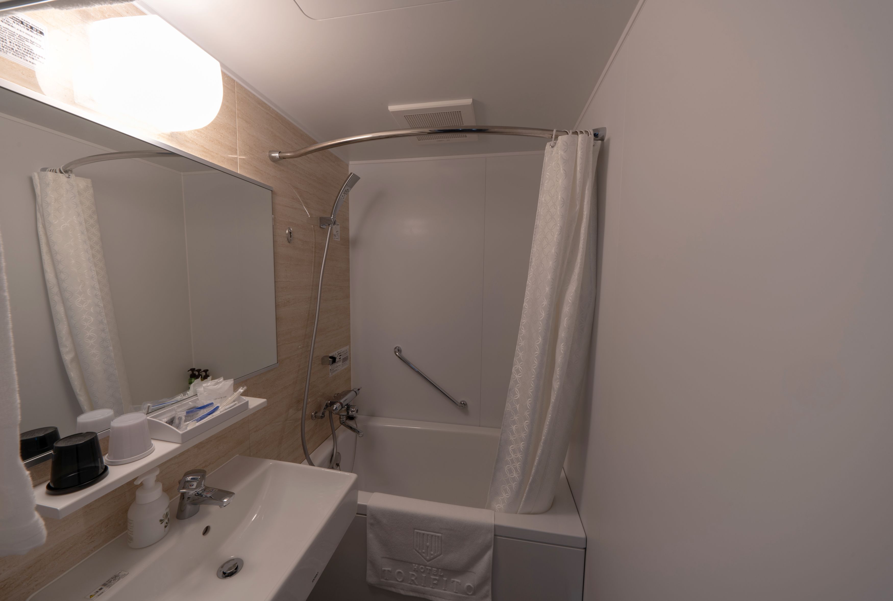 A modern bathroom with a sink, mirror, shower, and towel rack.