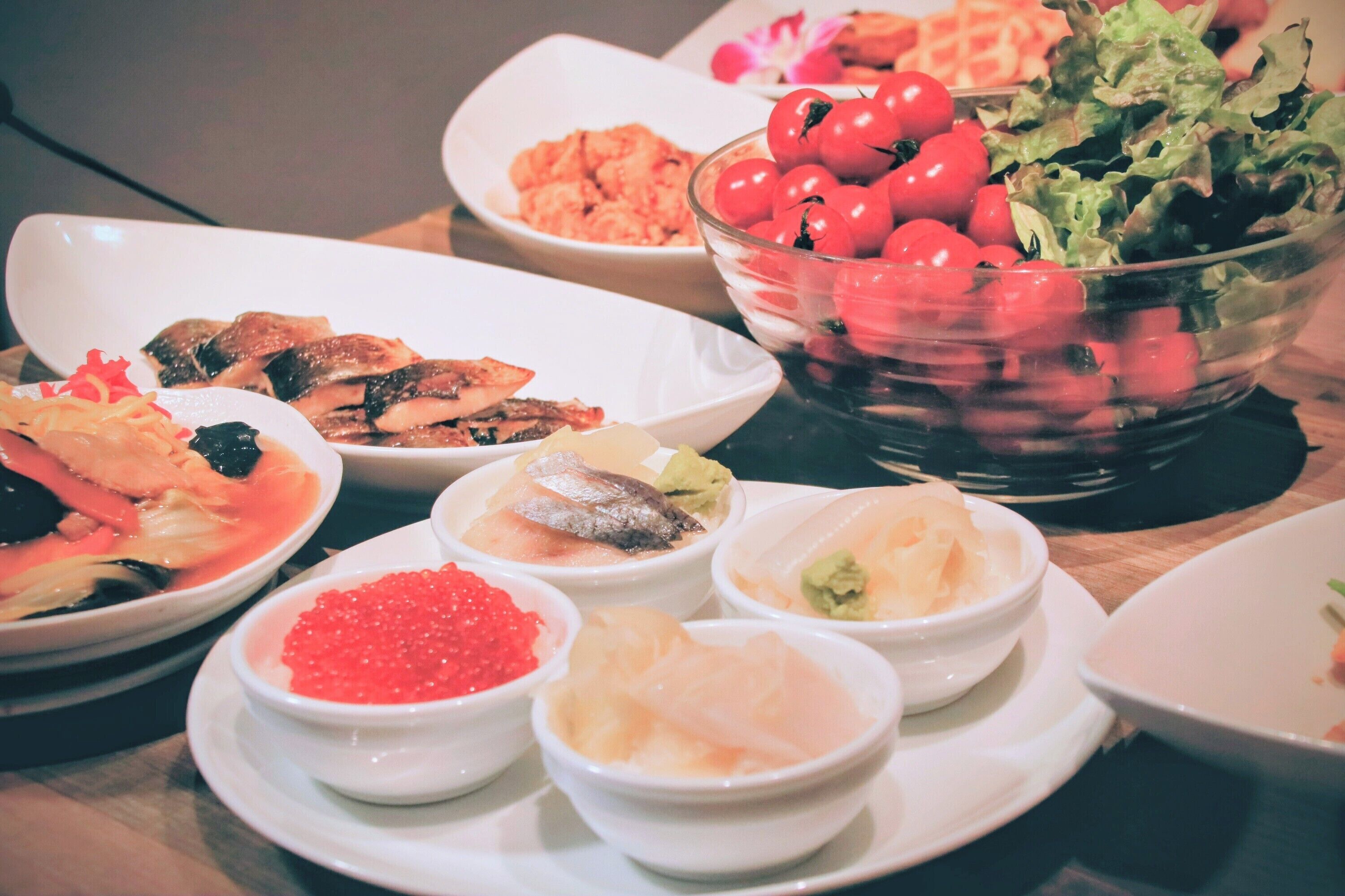 A variety of dishes on a table, including seafood, vegetables, and a bowl of cherry tomatoes.