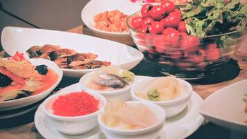 A variety of dishes on a table, including seafood, vegetables, and a bowl of cherry tomatoes.