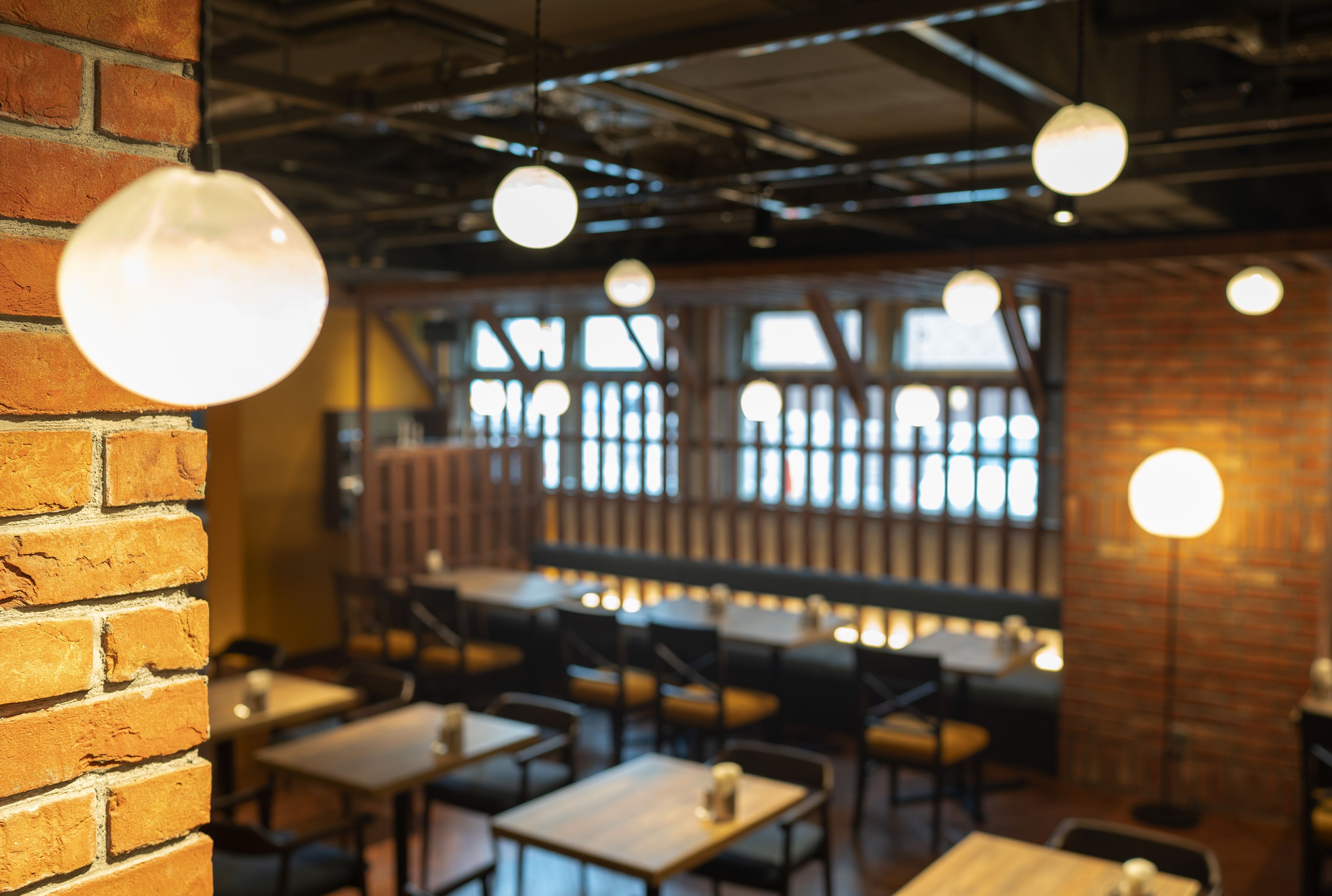 A restaurant interior with brick walls, hanging spherical lights, and tables arranged for dining.