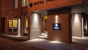 Entrada de hotel com uma placa indicando "HOTEL TORIFITO" e uma placa menor abaixo.