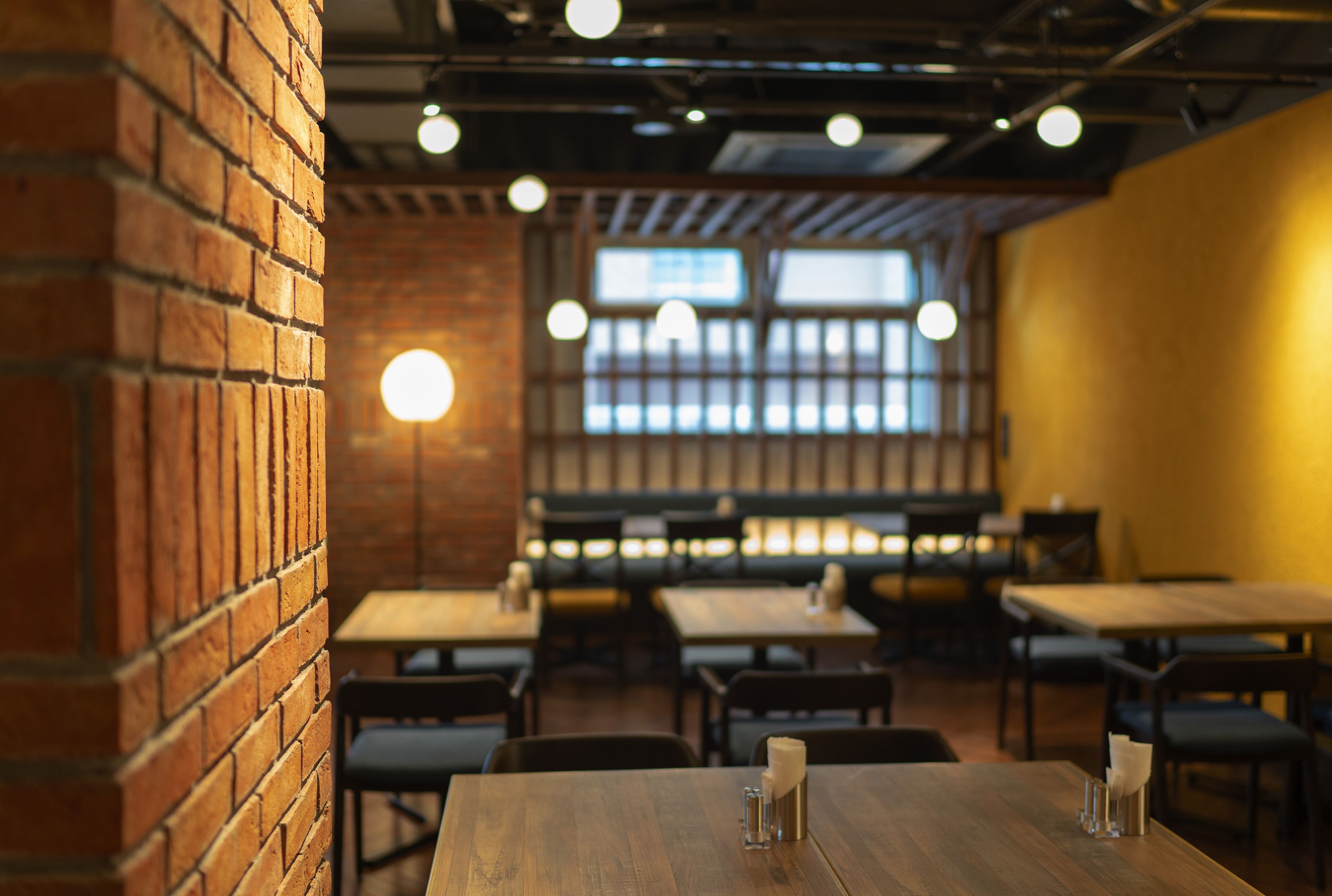 A restaurant interior with brick walls, wooden tables, and hanging lights.