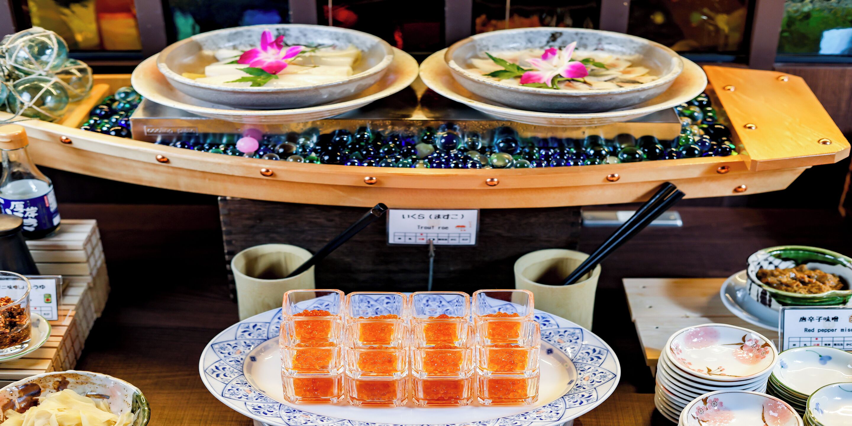 Montaje de bufé con diversos platos, incluyendo tazones de comida y una fuente de caviar rojo.