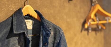 Een denimjas aan een houten kapstok met een label, en een gitaar hangt op een andere kapstok op de achtergrond.