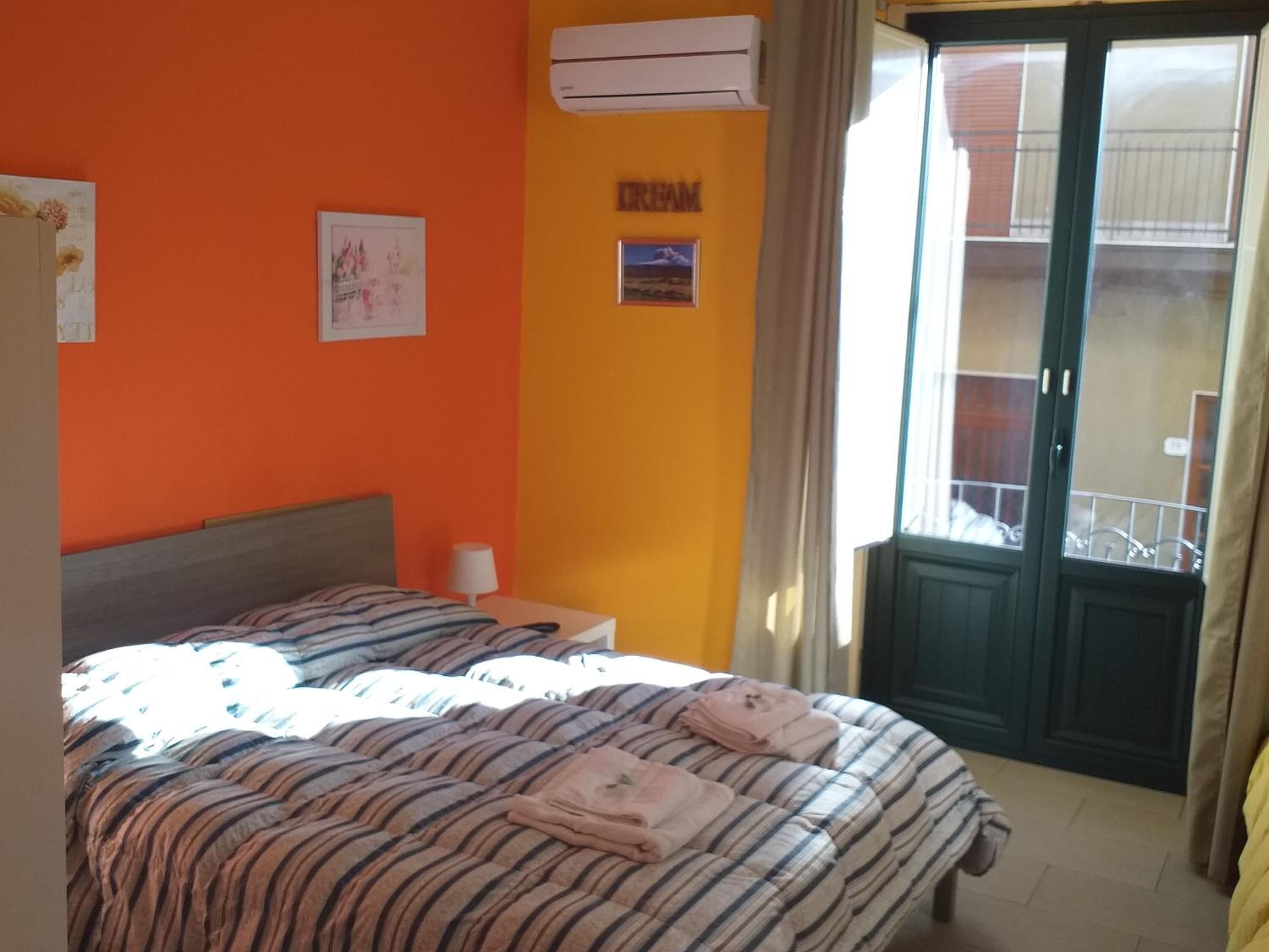 Un dormitorio con dos camas, aire acondicionado, ventana con vistas y puerta a un balcón.