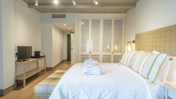 Una habitación de hotel con una cama grande, un escritorio con televisor y un armario con puertas de cristal.
