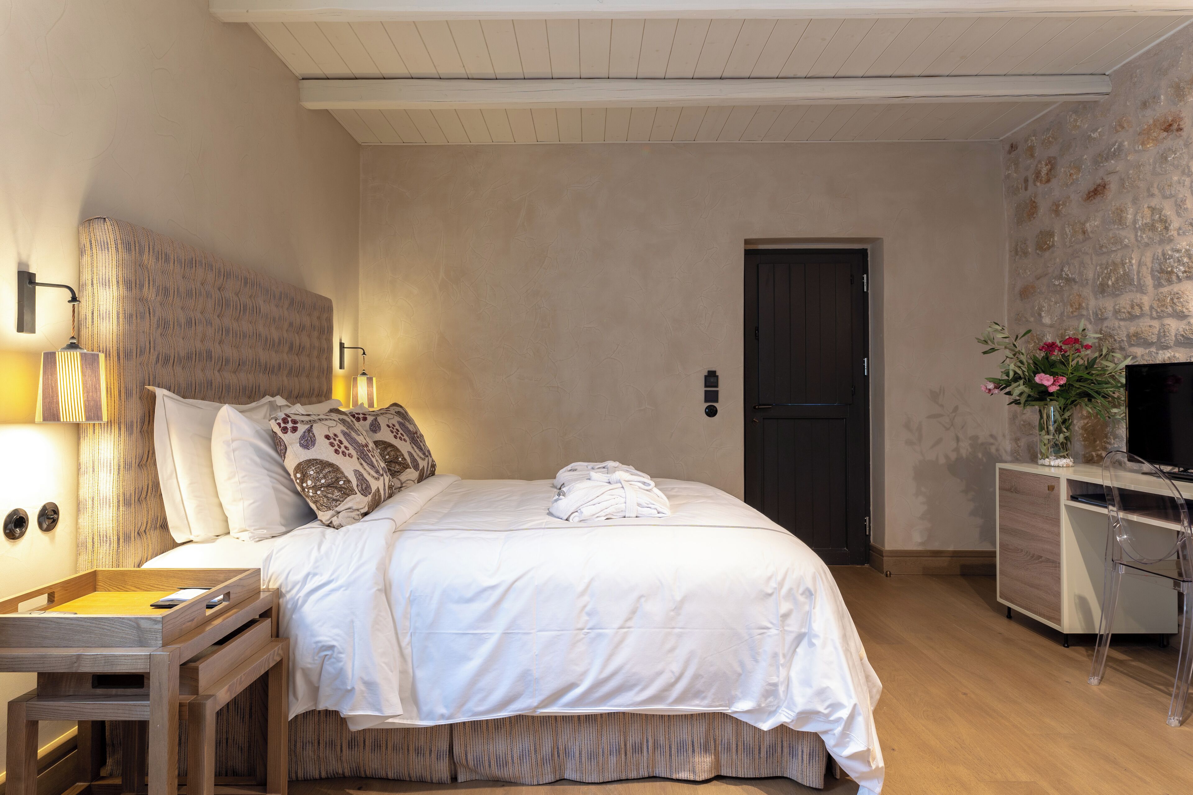 Une chambre à coucher bien rangée, avec un lit, des tables de chevet, un bureau et un téléviseur.