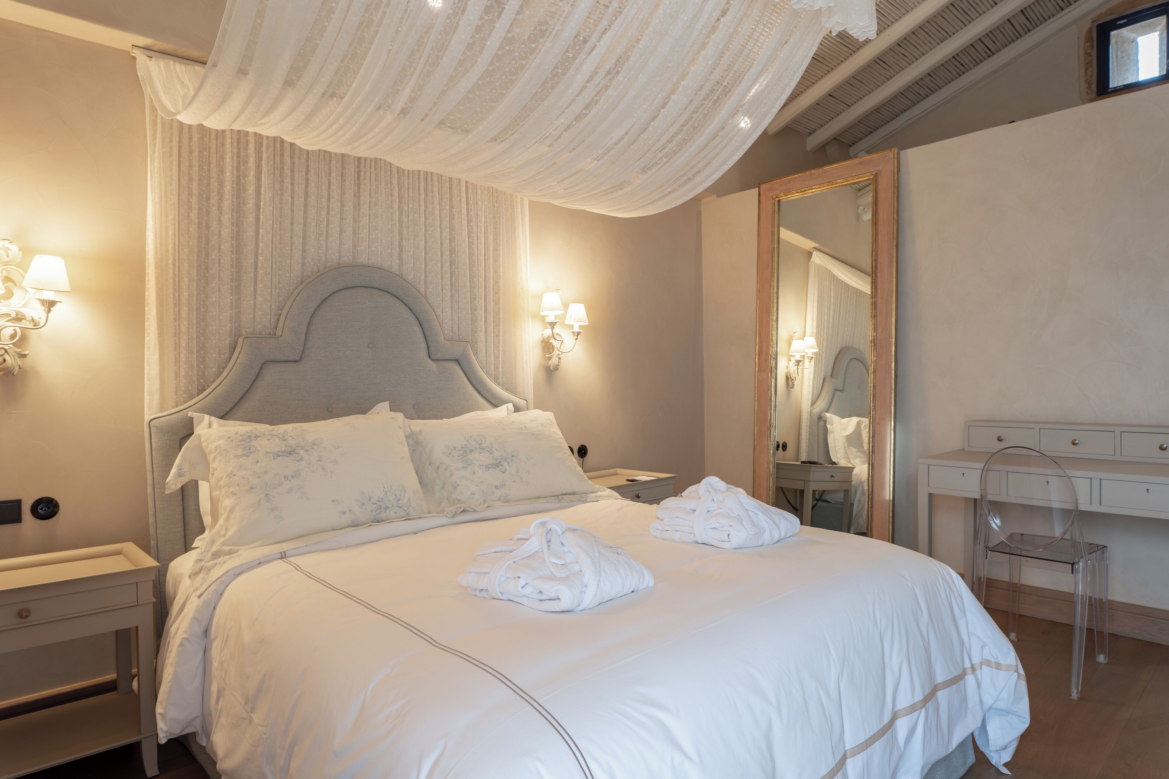 Habitación de hotel con una cama grande, dos lámparas de pared, una mesita de noche, un escritorio y una silla.