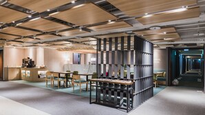 A modern office space with a central black shelving unit, wooden tables, and chairs. - Hej Taipei (Taipei)
