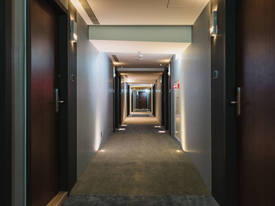 A long, narrow hallway with doors on both sides, leading to individual rooms.