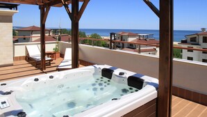A hot tub on a balcony with a view of the sea and neighboring buildings. - Long Beach Resort & Spa (Dolni Chiflik)