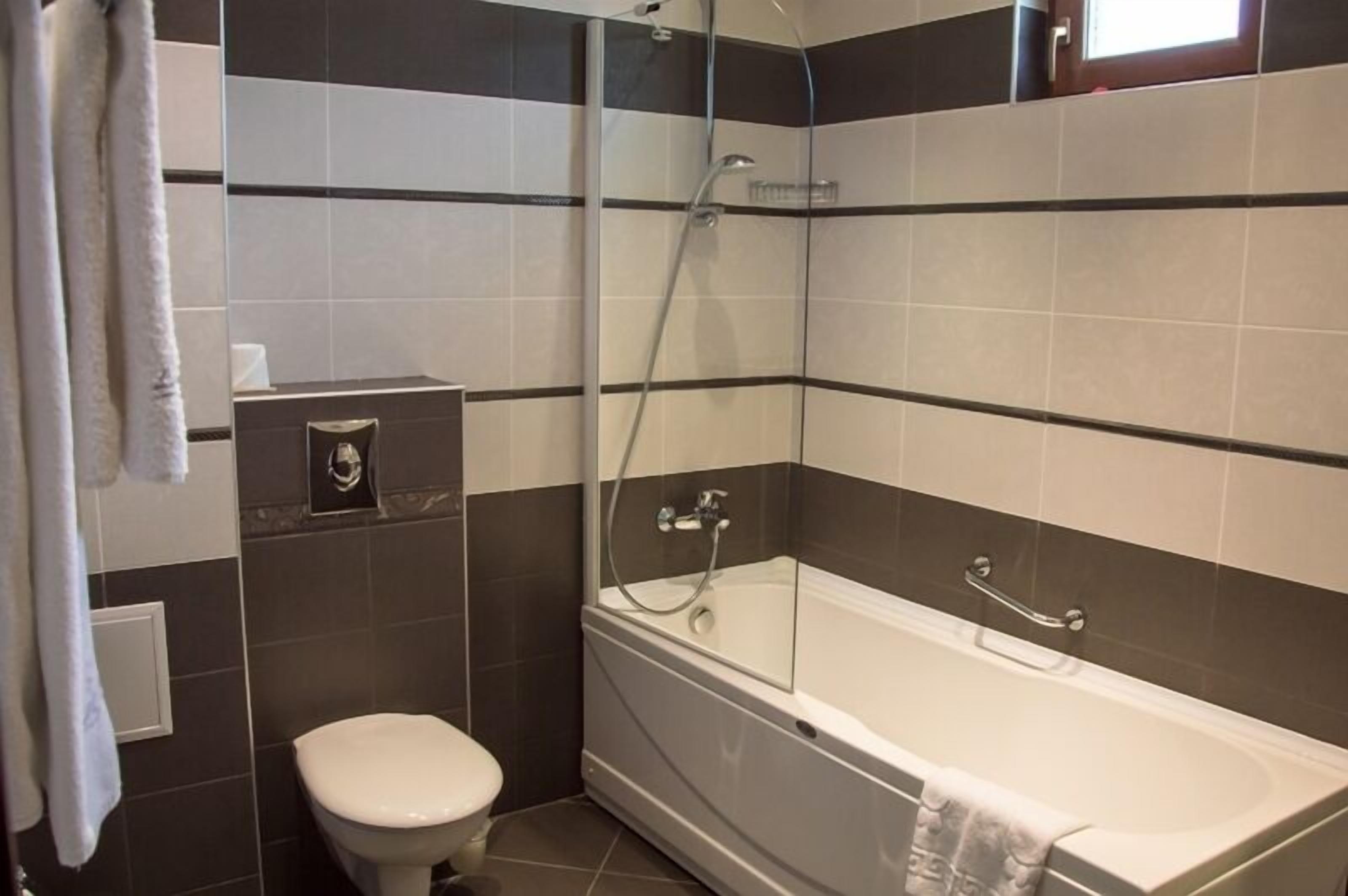 A bathroom with a bathtub, a toilet, and a glass shower enclosure.
