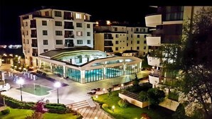 A modern hotel with a central swimming pool, multiple balconies, and a well-lit outdoor area. - Long Beach Resort & Spa (Dolni Chiflik)