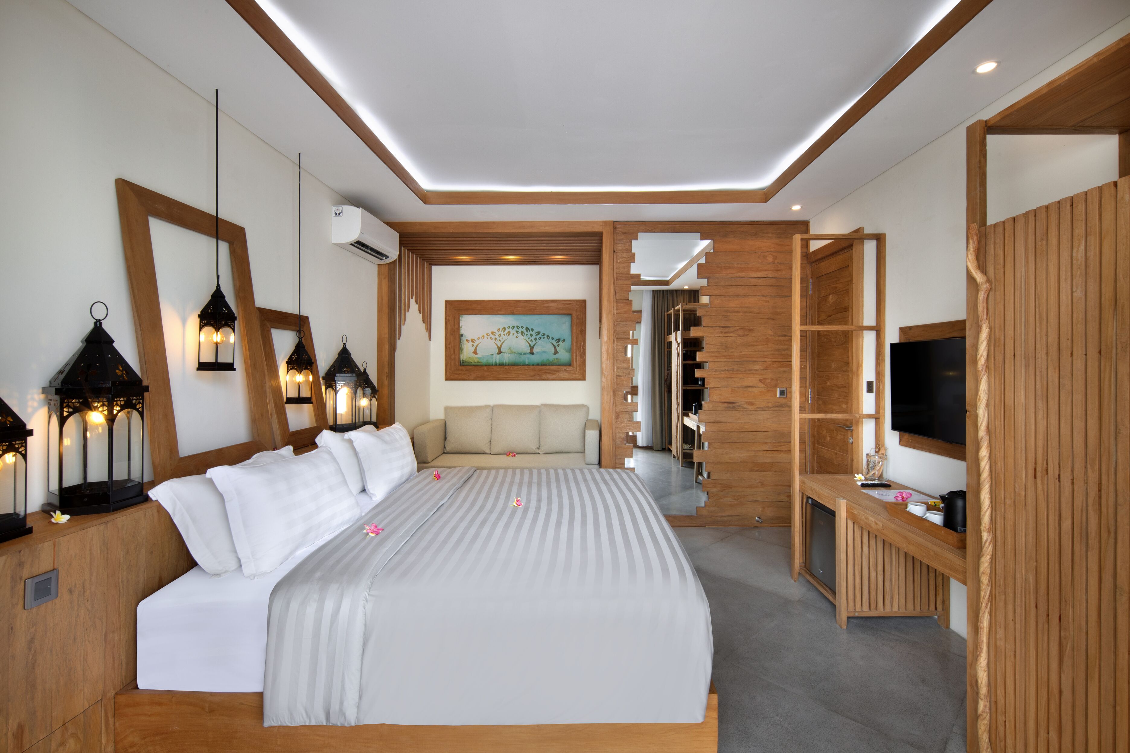 A modern bedroom with a large bed, bedside lamps, a painting, a sofa, and a TV.