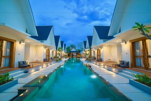 Ein modernes Resort mit einem zentral gelegenen Pool, Sitzbereichen im Freien und einem symmetrischen architektonischen Design.