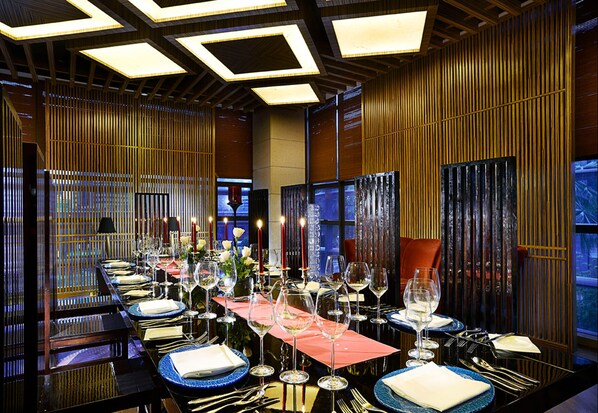 A restaurant with multiple tables set for dining, featuring a modern interior with wooden paneling and recessed lighting.