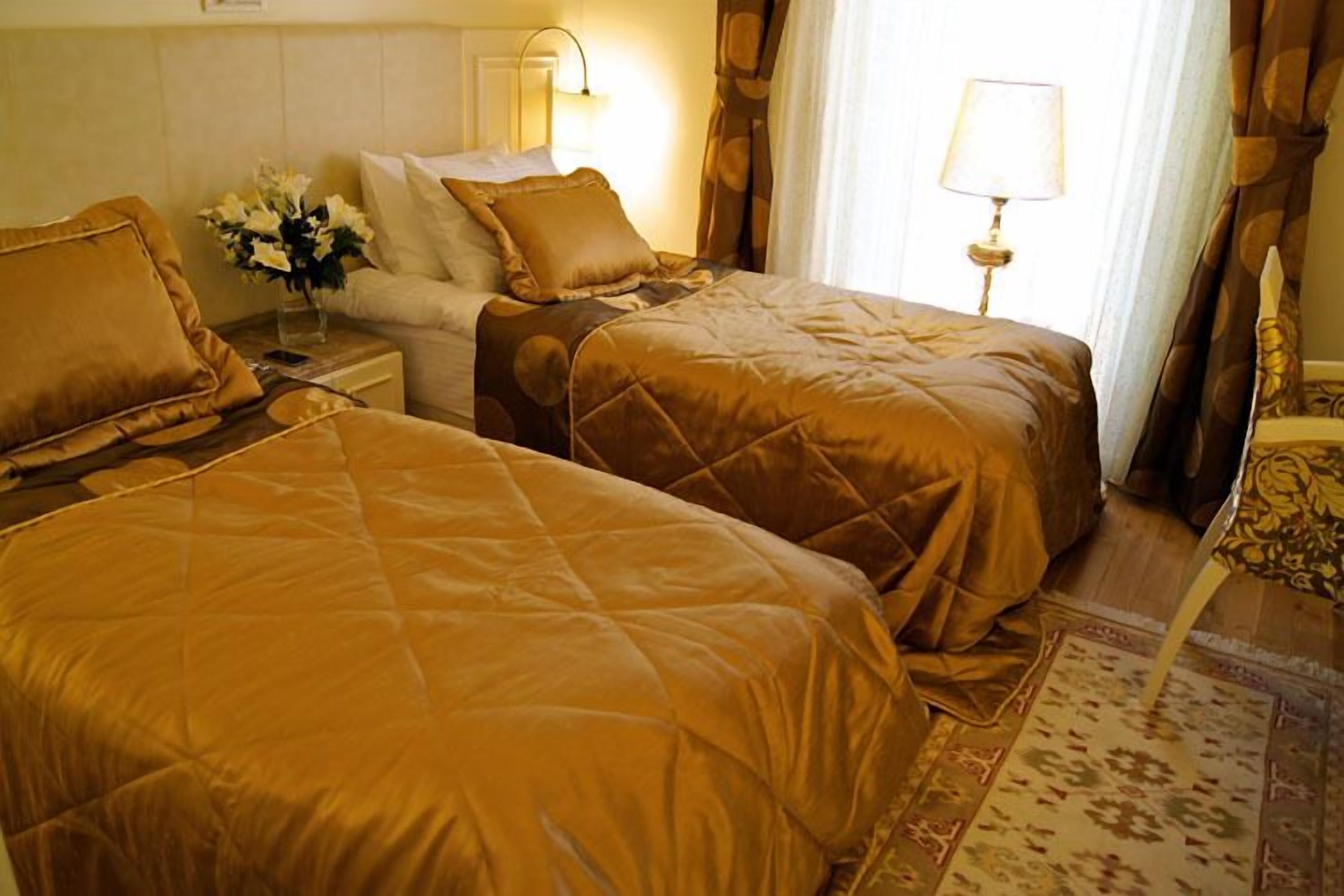 Una camera d'albergo con due letti, un comodino, una lampada e un bouquet di fiori.