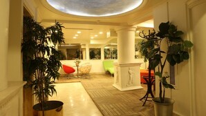 A spacious lobby with a high ceiling, large columns, and potted plants. - Hotel Gelibolu (Gallipoli)