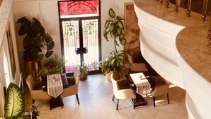 A spacious indoor area with a high ceiling, a balcony with a railing, and a view of a painting of a person on a beach. - Hotel Gelibolu (Gallipoli)