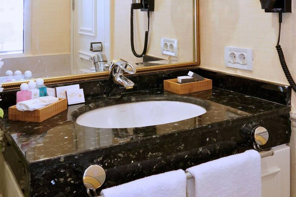 Une salle de bain avec un grand lavabo, un miroir et un porte-serviettes.