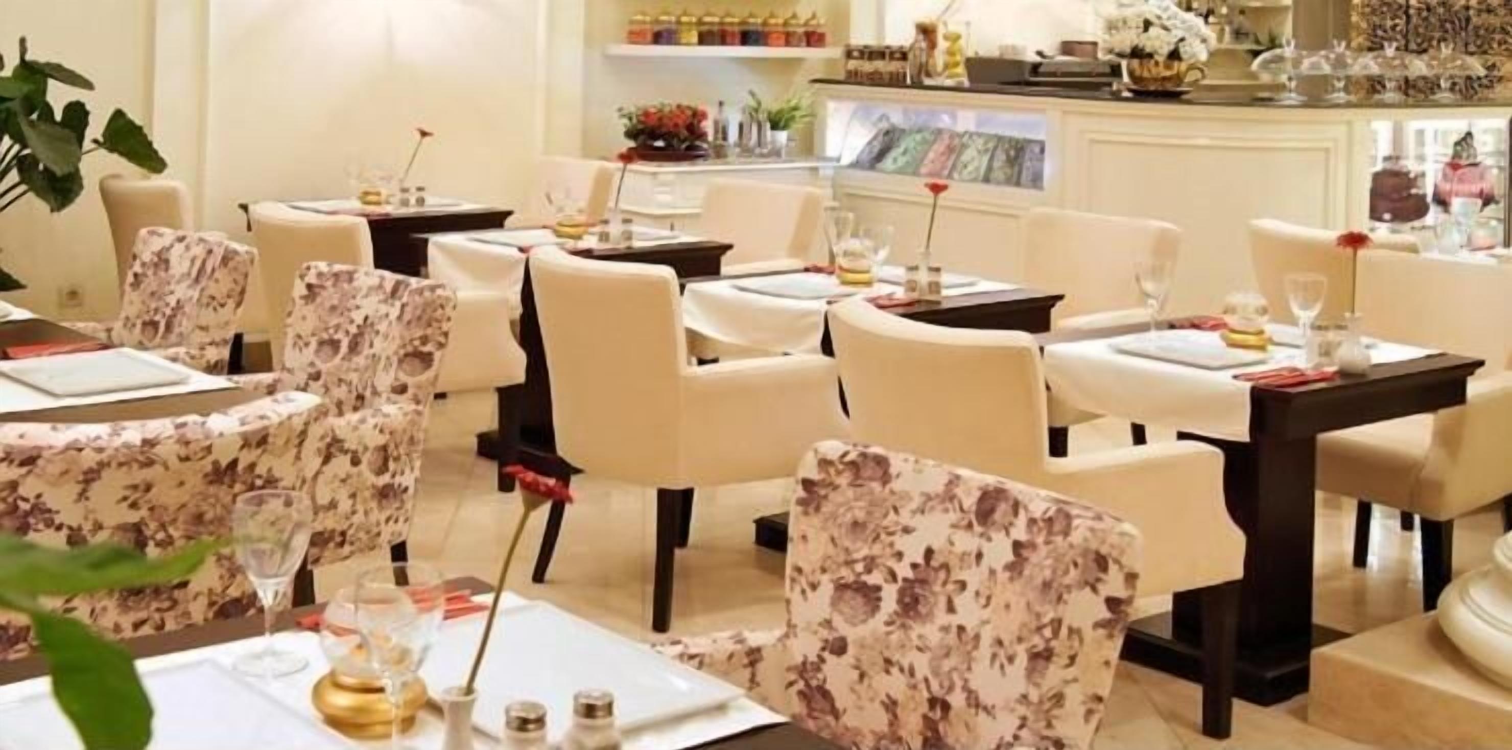 Un comedor con mesas redondas, sillas y una zona de bar con mostrador y elementos decorativos.