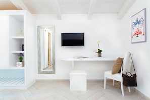 A modern living room with a white sofa, a TV mounted on the wall, a small table with a plant, and a decorative mirror. - Villa Totti (Sant'Agnello)
